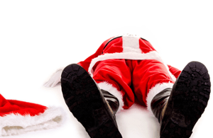 Ein Mann im Weihnachtsmannkostüm liegt auf den Boden. Links von ihm liegt seine Mütze.
